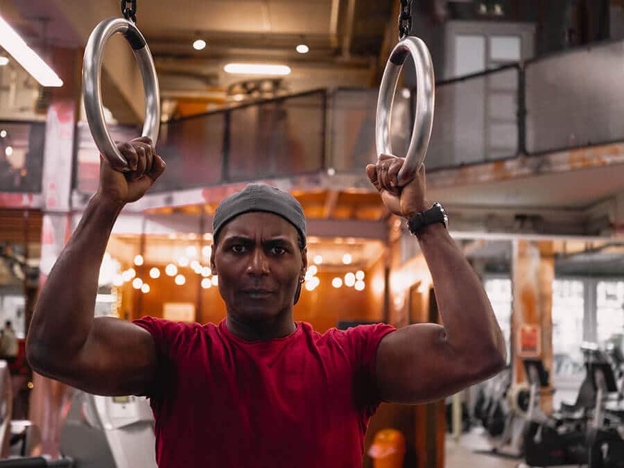Mann in der Fitnessfabrik beim Functional Training an Ringen